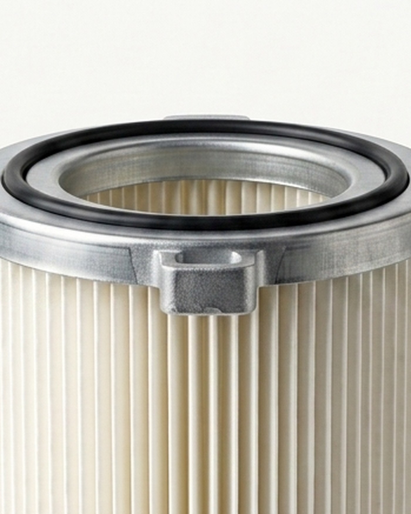 Close-up of a cartridge filter top flange: galvanised steel rim with bayonet lugs and a black O-ring seal, above pleated filter media.